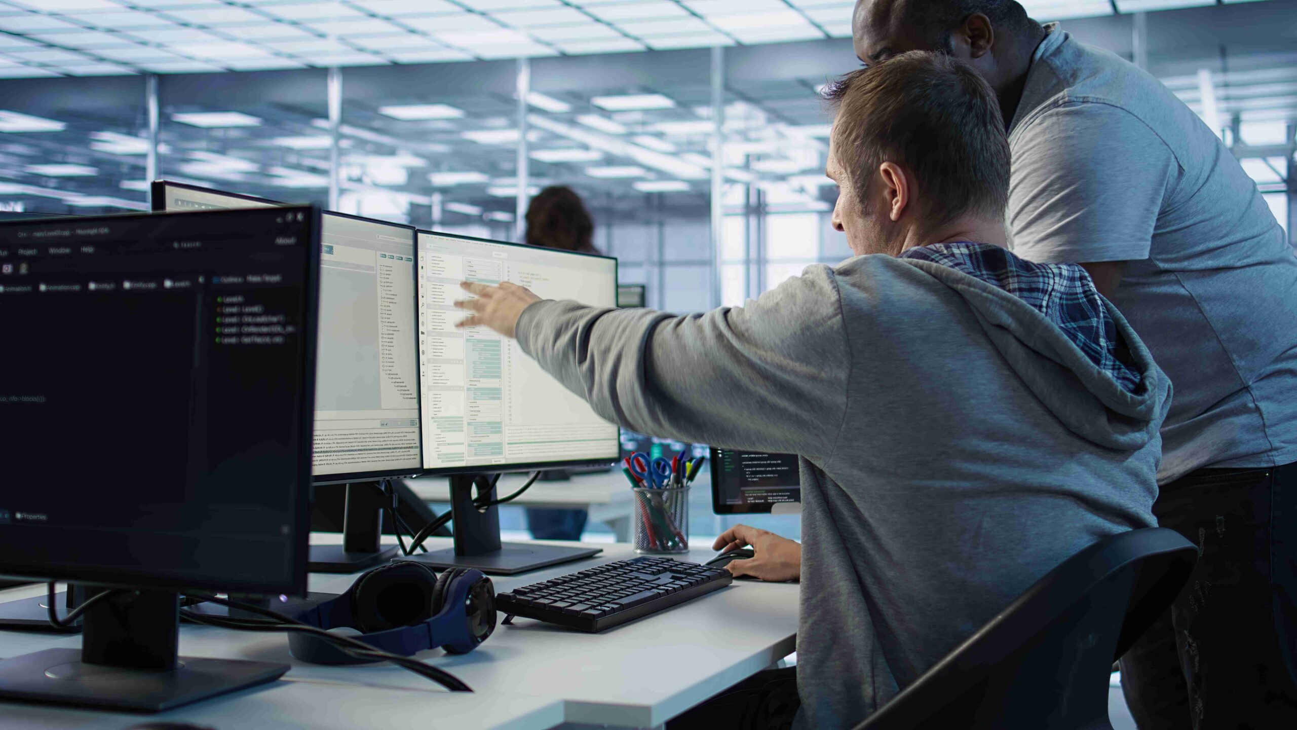 Programmer requesting help from manager while working on computer in data center, monitoring hardware energy consumption. Team leader overseeing IT expert checking for system failures, camera B