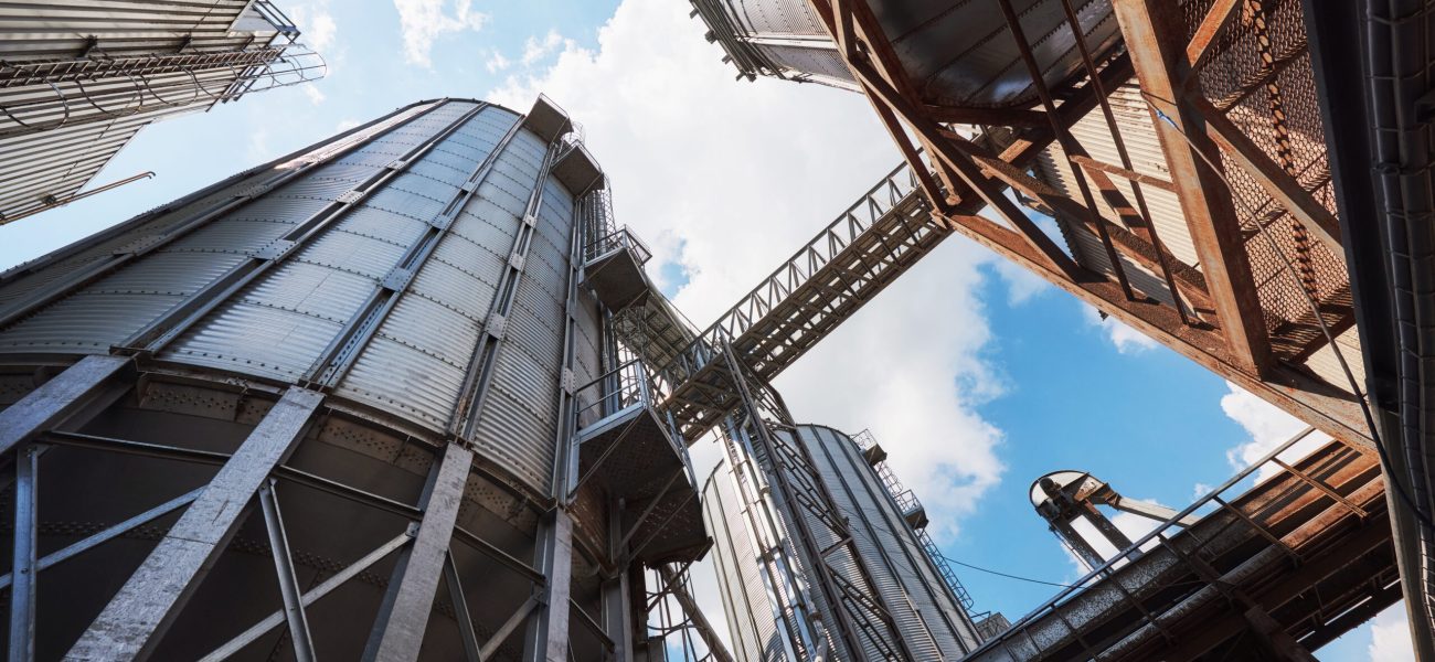 Agricultural Silos. Building Exterior. Storage and drying of grains, wheat, corn, soy, sunflower against the blue sky with white clouds.